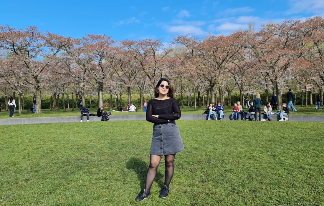 ACCESS Stories - August 2026. Finding Home Between People. Photo of Maryam Mollaei in a park with blooming trees.