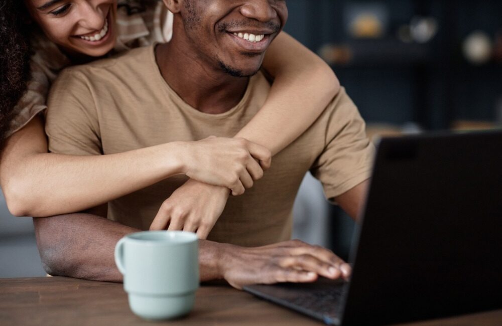 Registered partnership and children: what happens when your family crosses a border? Hugged couple looking at a laptop screen.