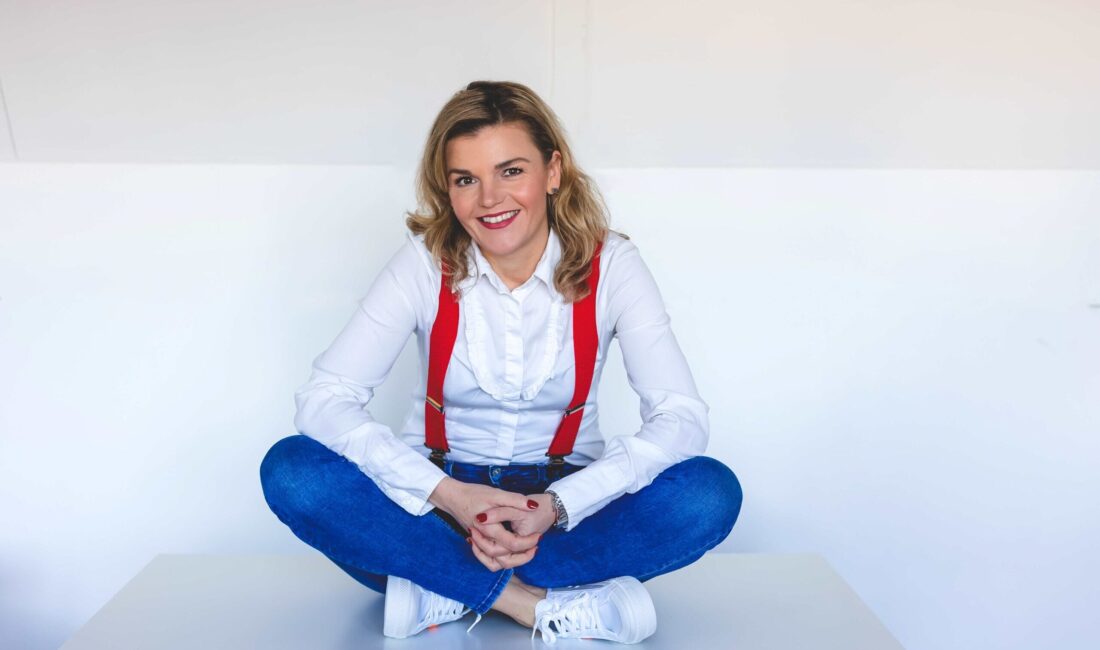 ACCESS Stories September 2026. -----. Beata sitting with her legs crossed, smiling at the camera.
