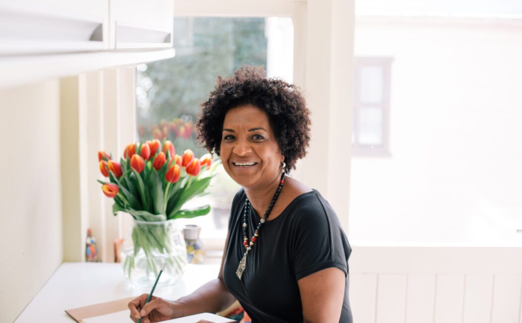 ACCESS Stories - October 2026. Rebuilding My Life in the Netherlands. Rawia at her desk smiling.